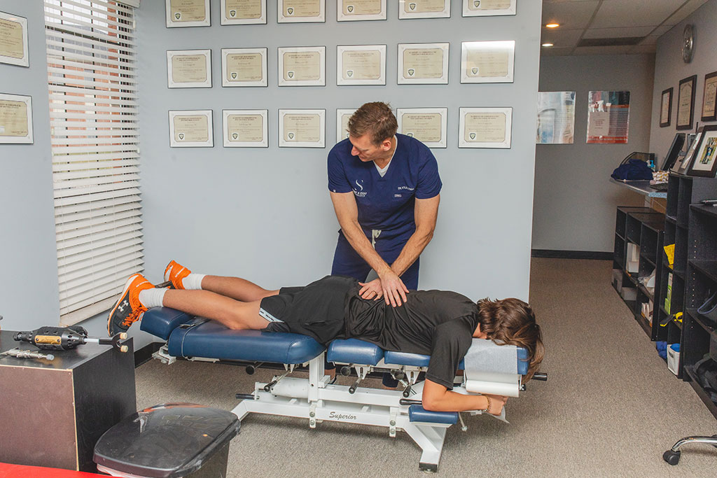 Dr. Longo adjusting the back of a young man during chiropractic treatment for back pain