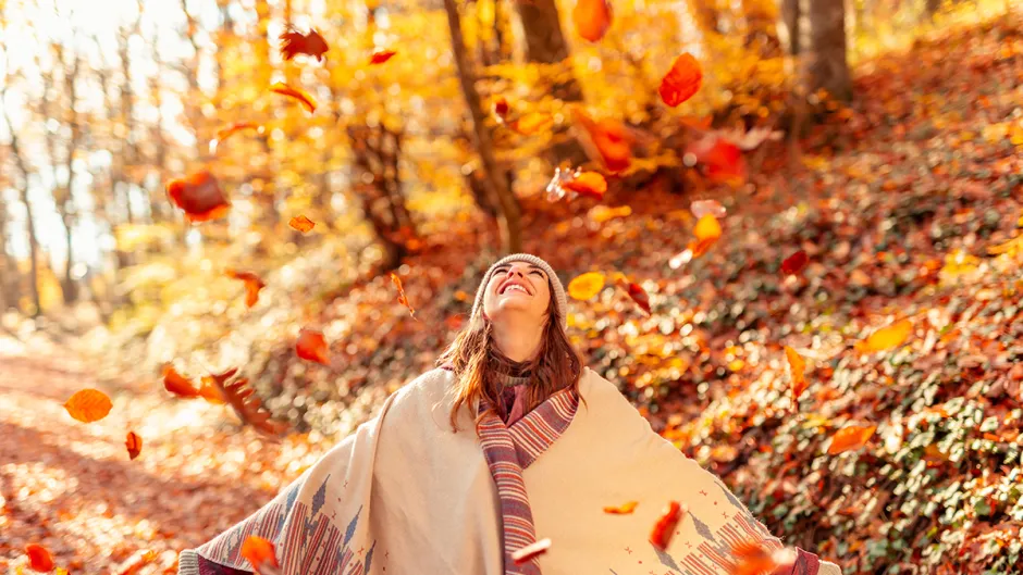 woman standing in the woods during autumn, enjoying nature