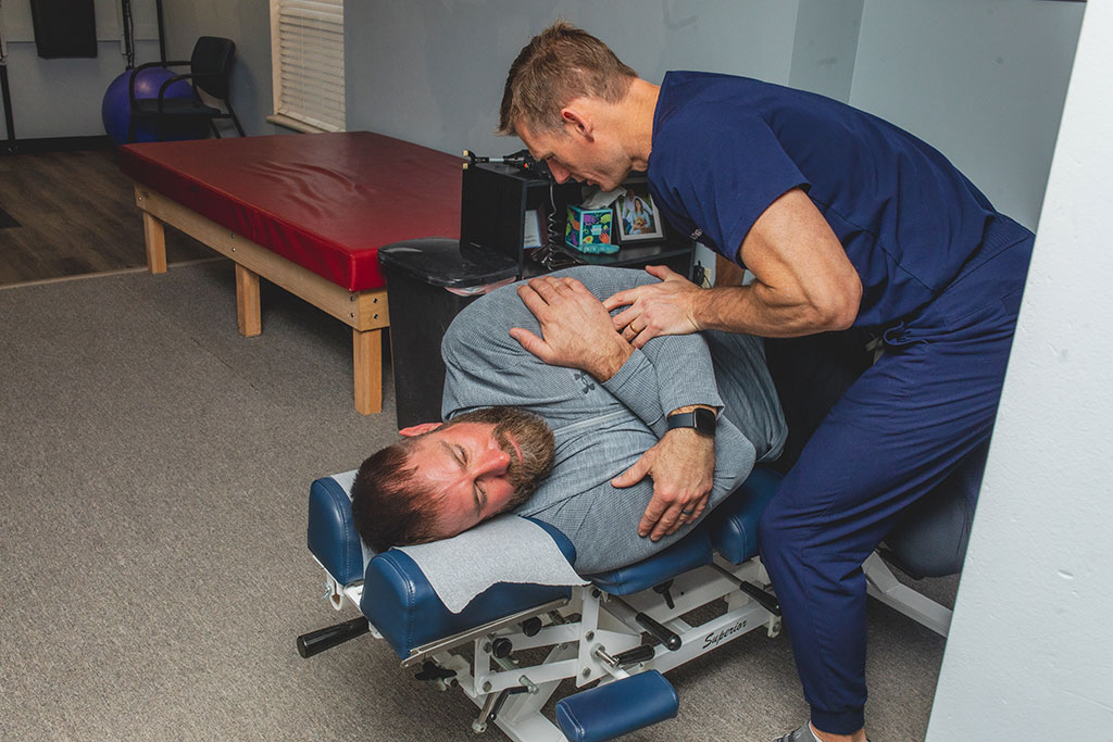 Dr. Longo adjusting the back of a young man during chiropractic treatment for back pain